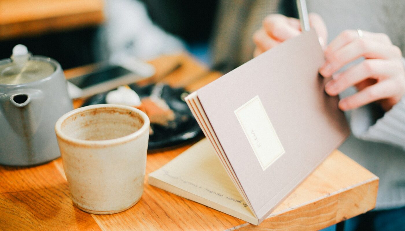 person opening book near coffee cip