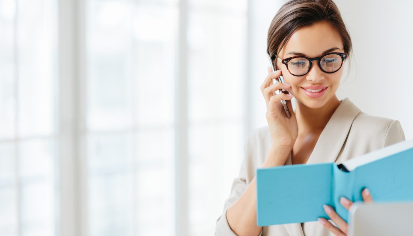 Satisfied brunette woman in transparent glasses has telephone conversation