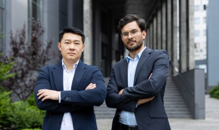 Confident business professionals standing outside modern office building with arms crossed